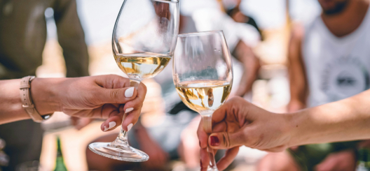 Image of clinking glasses of white wine.